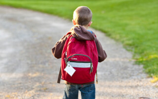 A young child walking down a road with a red backpack - Keep pests away form your home with Terminix Wil-Kil